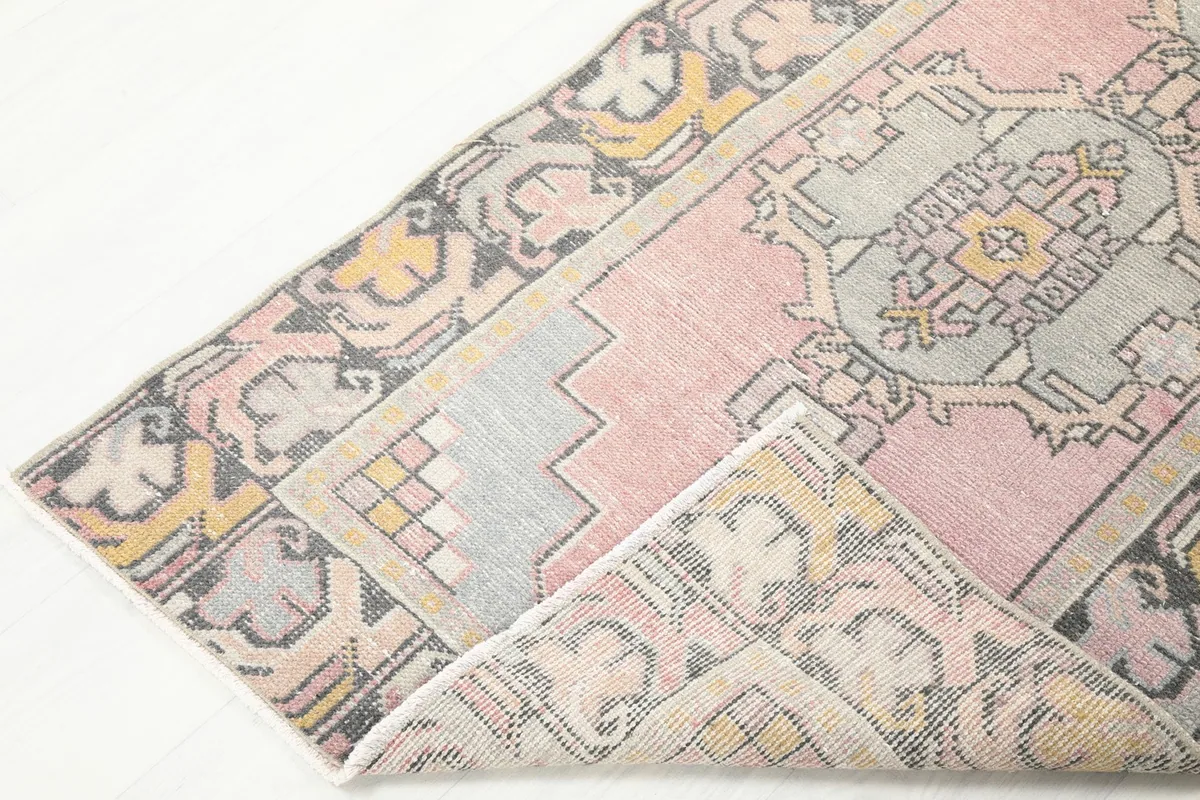 View of the runner rug partially folded, showing the flexibility and thickness of the vintage wool material.