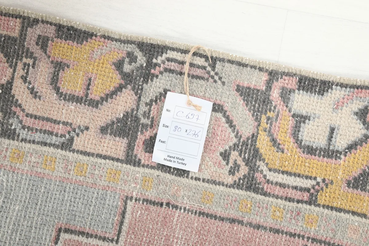 Close-up of the rug's surface with a product tag, showing the texture and colors of the vintage wool.