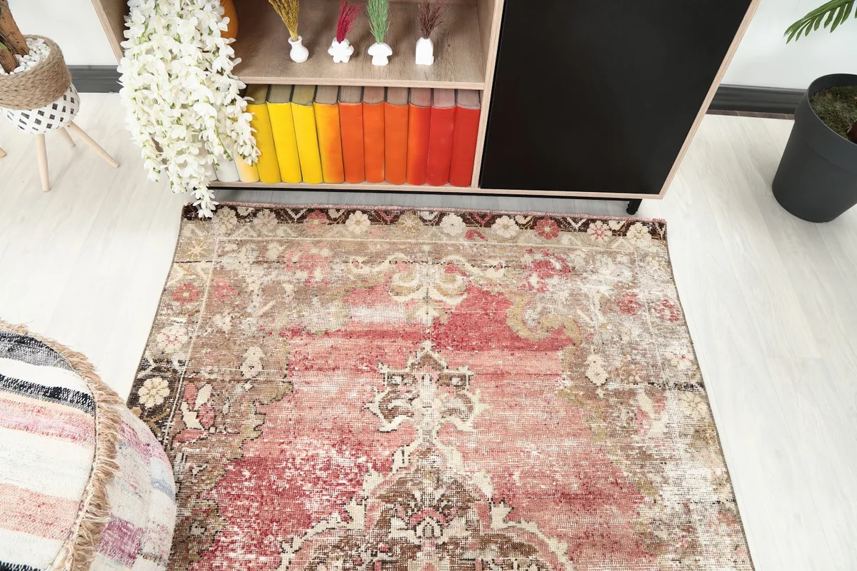Downward angle view capturing the rug's distressed rose and brown tones in a room