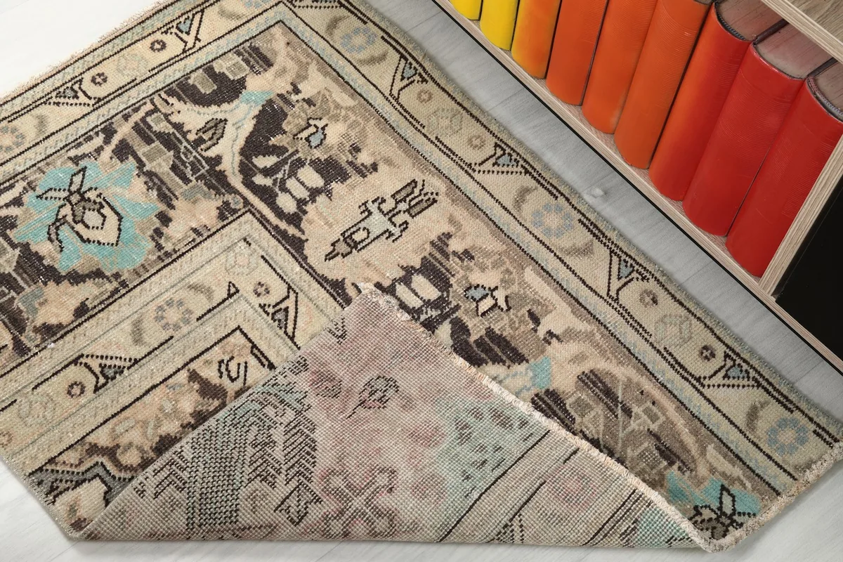 Corner of the rug folded back, revealing the cotton foundation and reverse side