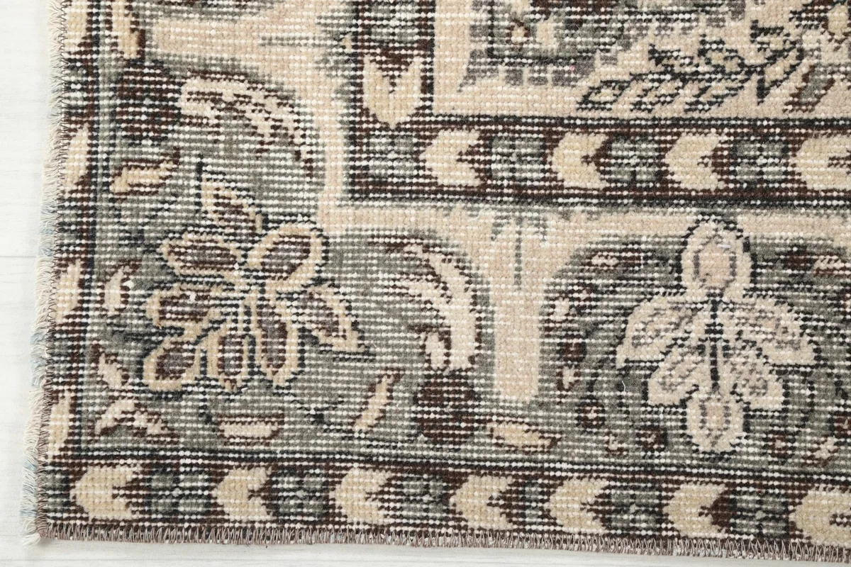 Detailed view of the rug's corner and border, showcasing the geometric and floral patterns and fringe