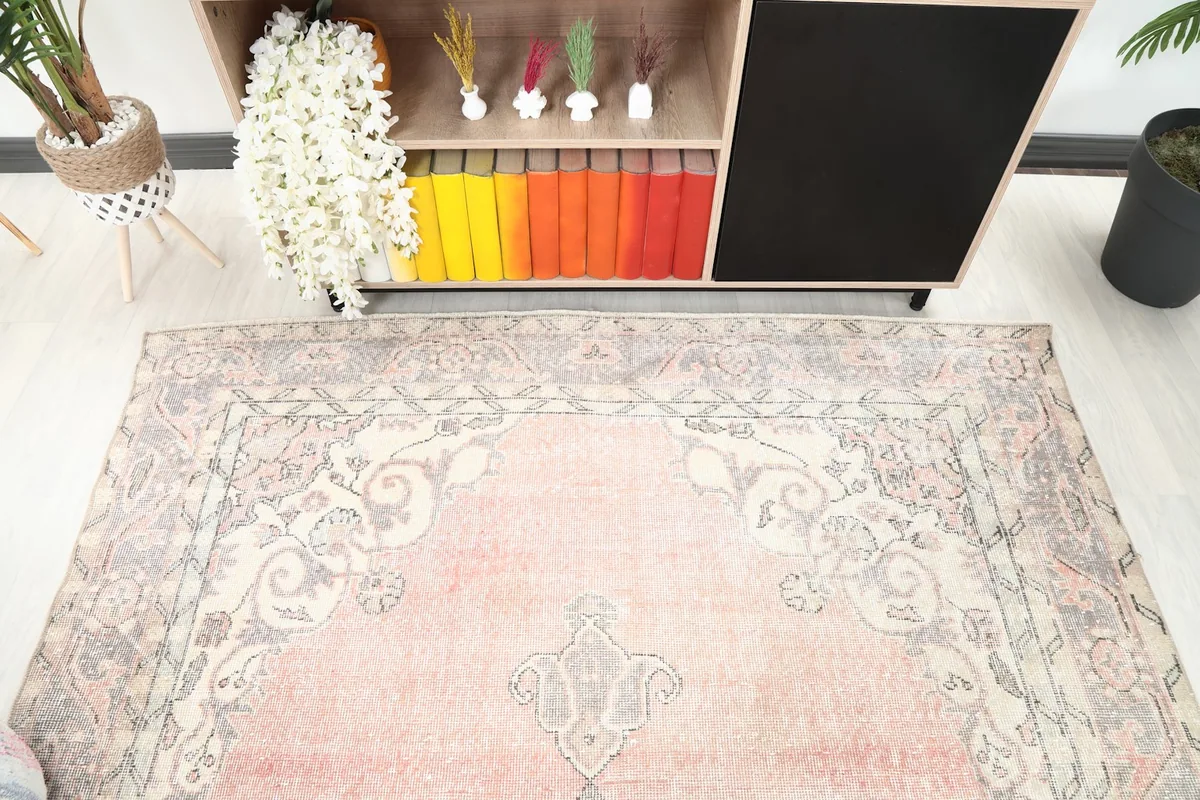 Detail angle of the top portion of the rose and gray vintage rug, showing border motifs and color variation.
