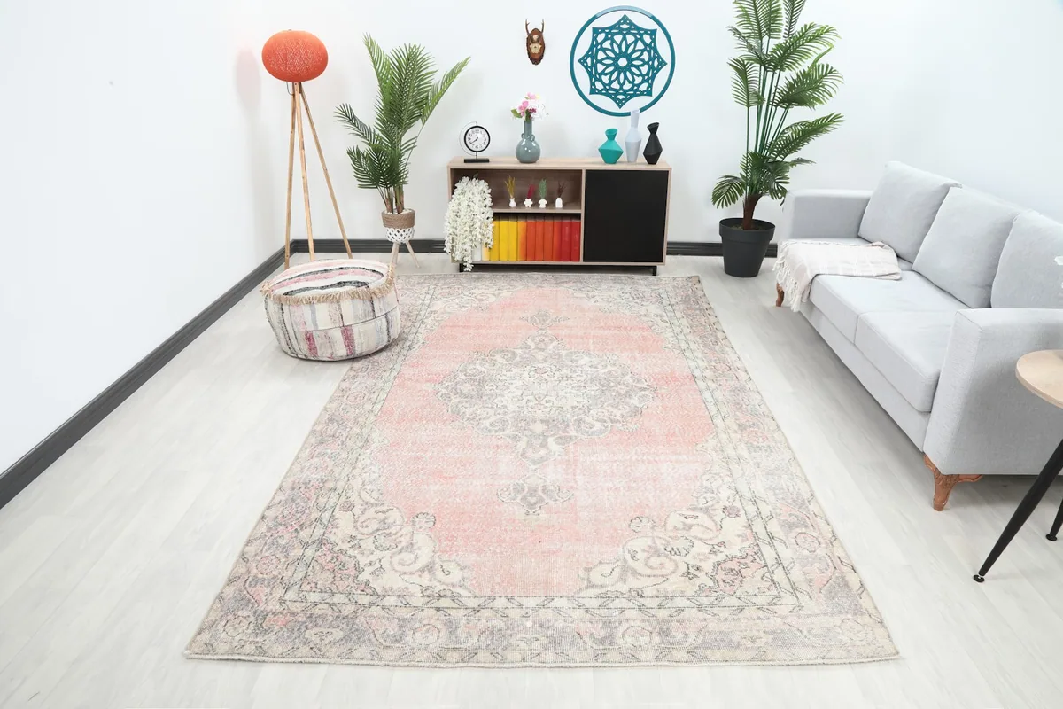 Vintage Anatolian rug with rose field and gray border in a modern living room setting with a gray sofa.