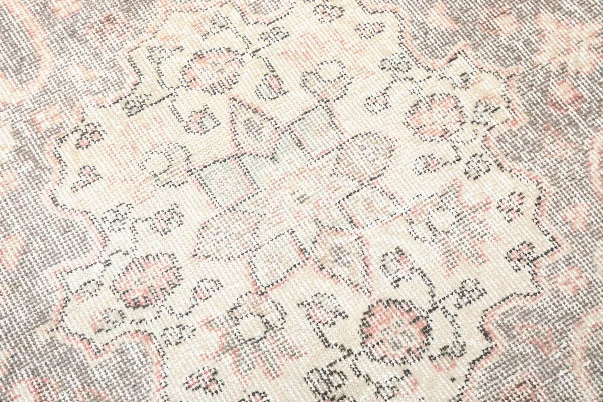 Detailed view of the intricate patterns and color variations within the gray medallion on the vintage rug.
