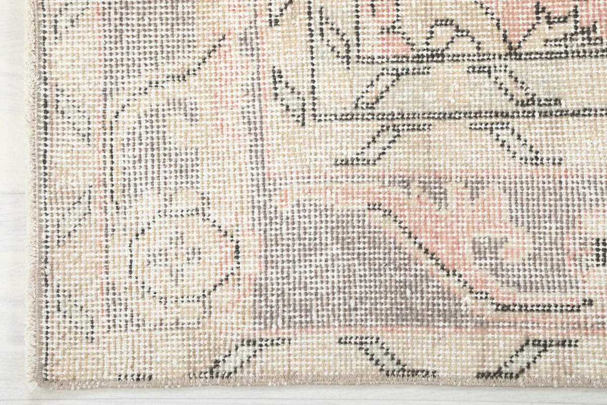 Close-up of the gray border pattern and edge of the vintage hand-knotted rug, showing weave and subtle wear.