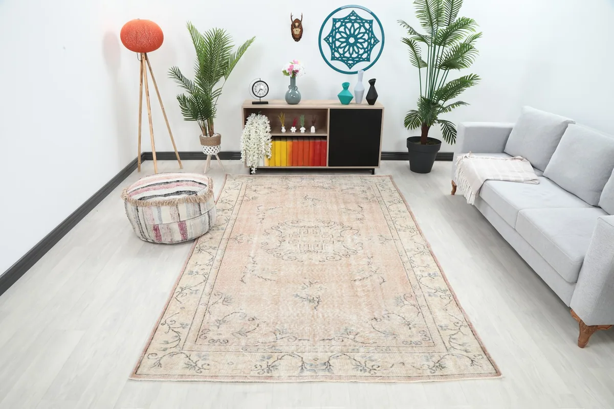 Wide angle view of the rose vintage rug placed in a modern living room setting with a light gray sofa.