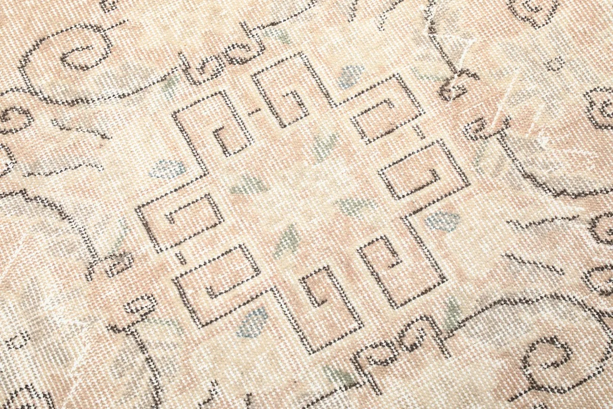Very close-up shot of the geometric medallion, revealing the texture and faded colors of the wool pile.