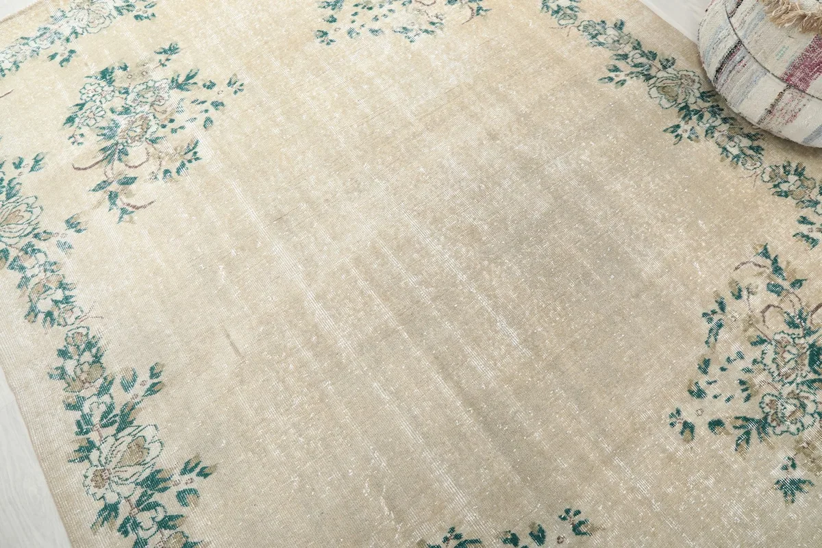 Corner view of the rug's floral motifs and the natural patina on the ivory background.