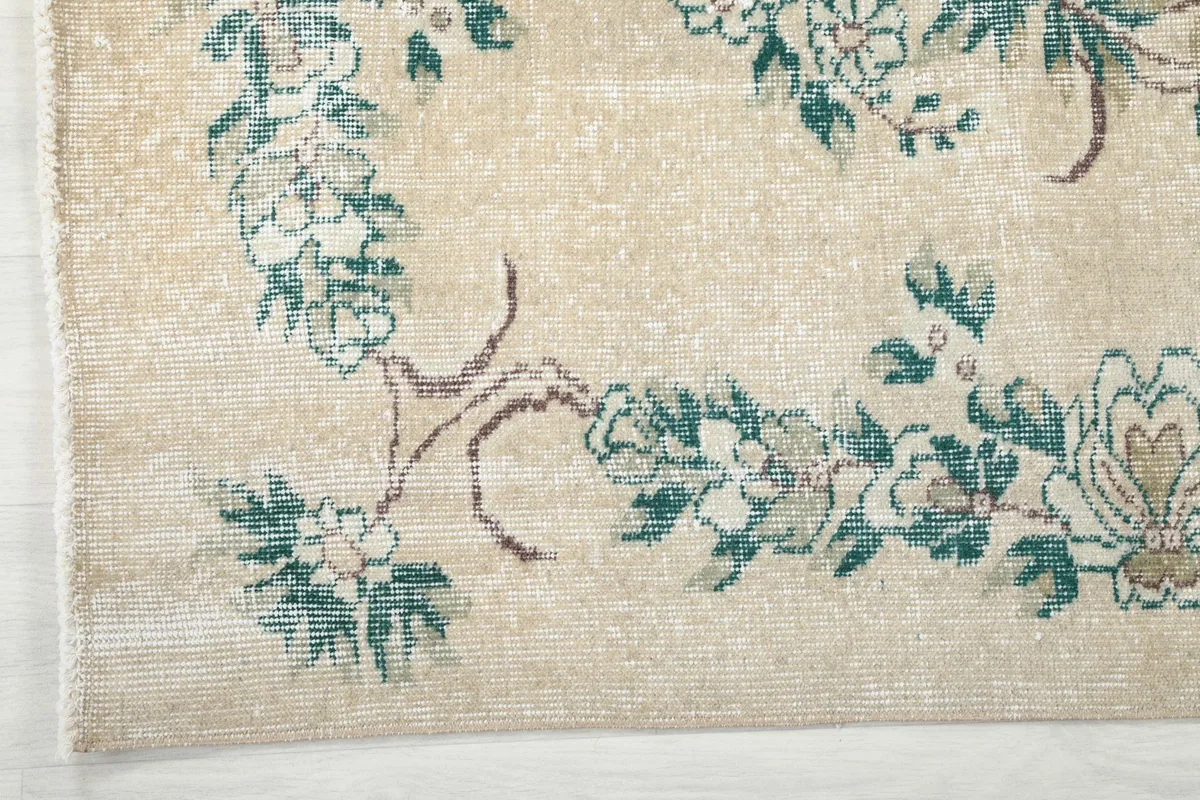 Detailed view of the green floral border and corner design, revealing the intricate knotting.
