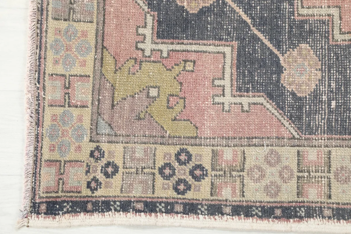 Close-up of the rug's corner, showing the outer border, fringe, and navy field.