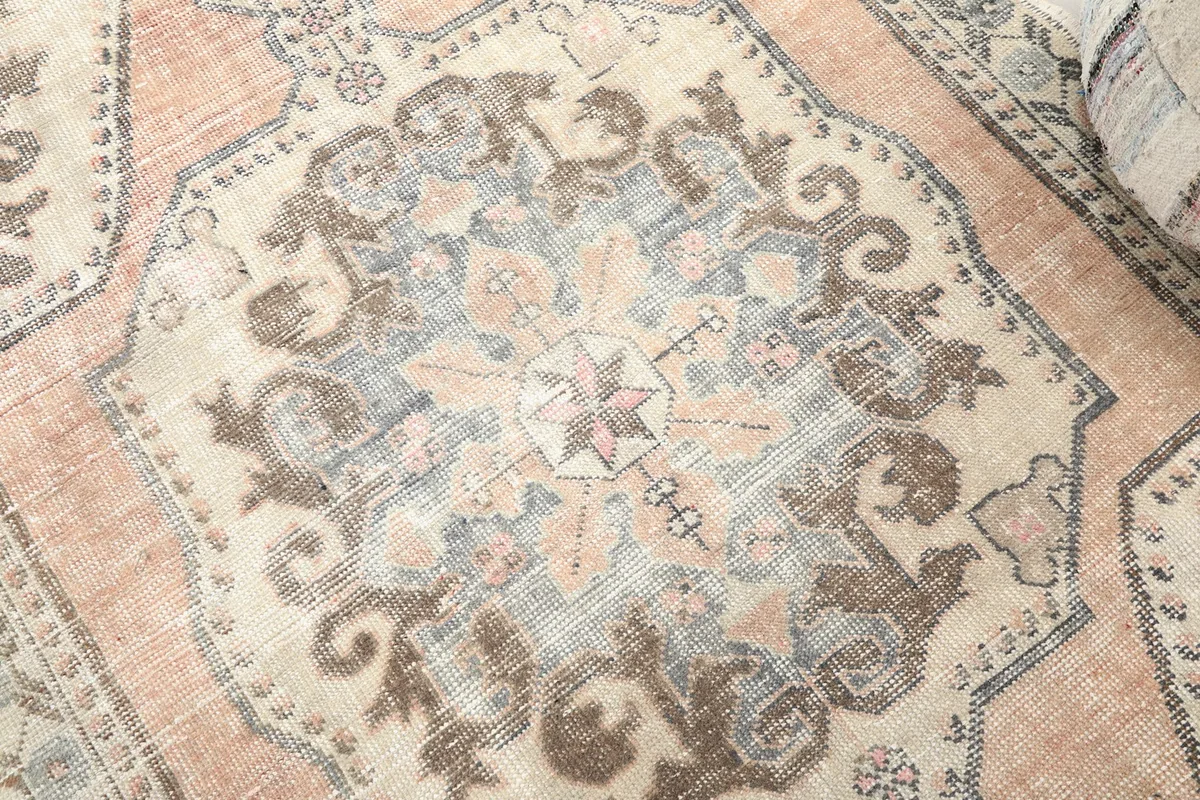 Detailed view of the central medallion motif, revealing the rose, gray, and beige colors.