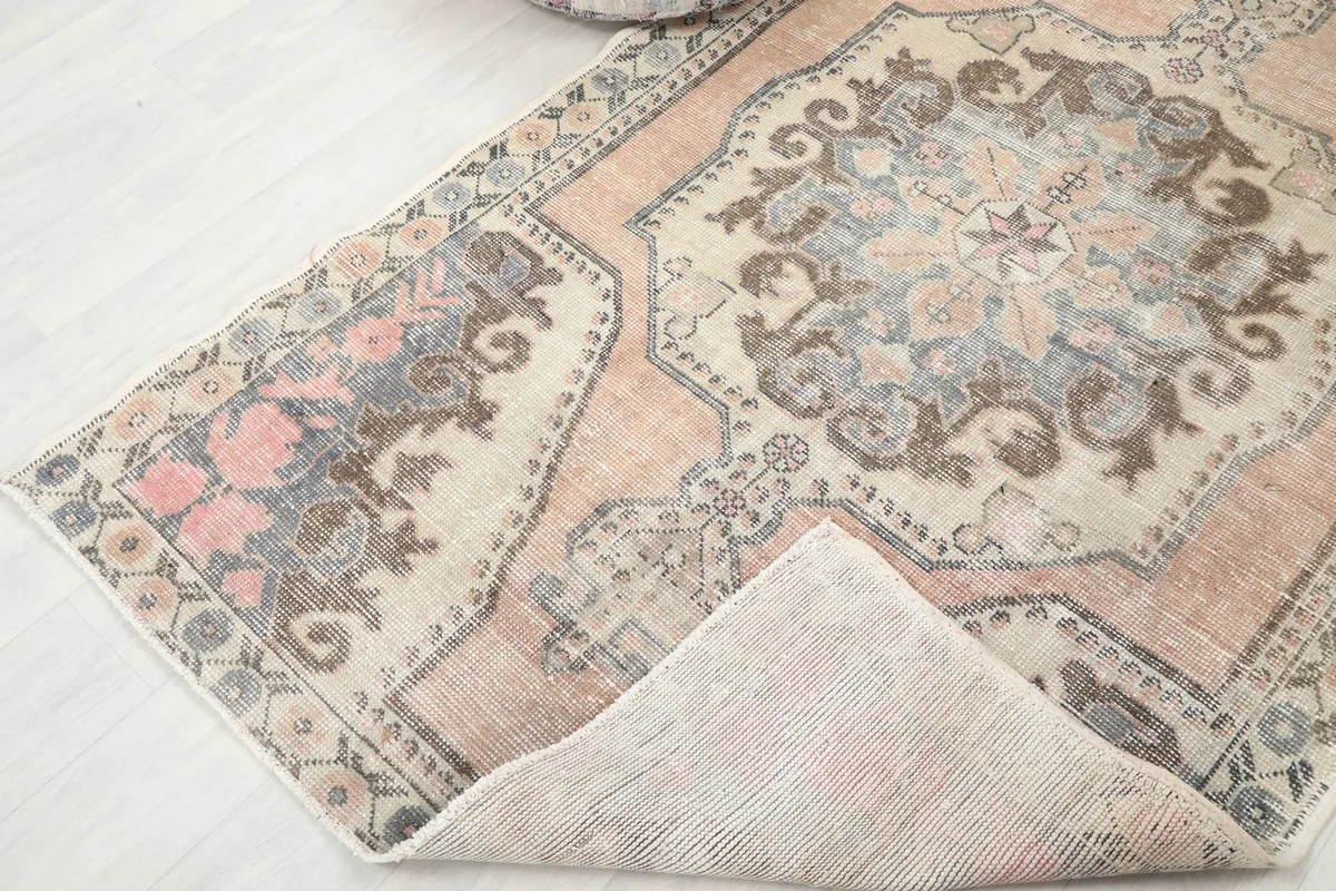 View of the rug with a corner folded back, showing the cotton foundation and reverse side.