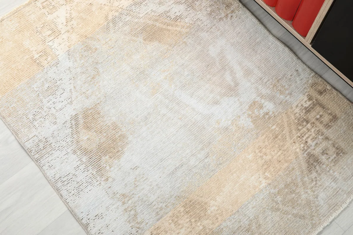 Detailed view of the rug's faded beige and tan colors with subtle geometric motifs.