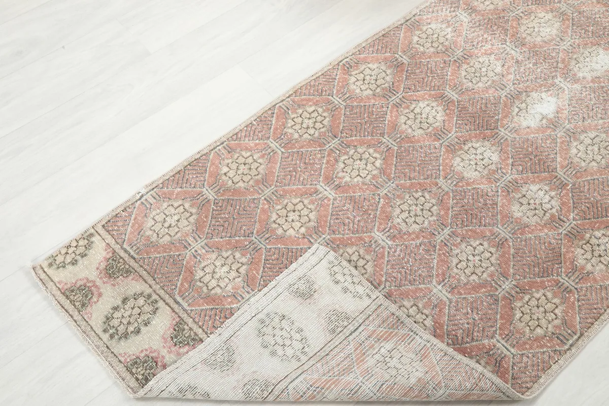 Corner of the runner rug folded back, revealing the reverse side of the hand-knotted wool.