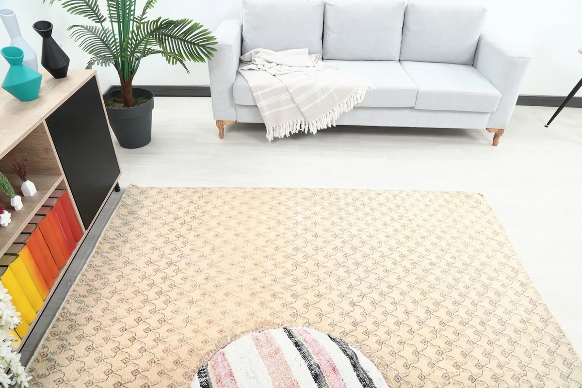 High angle view of the small beige and rose area rug in a room with a light gray sofa.