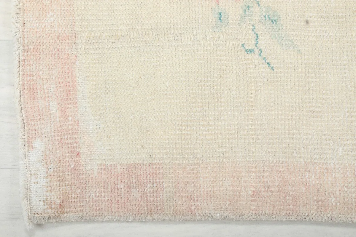Close-up of the faded rose border and edge of the runner rug, showing wear consistent with its age.