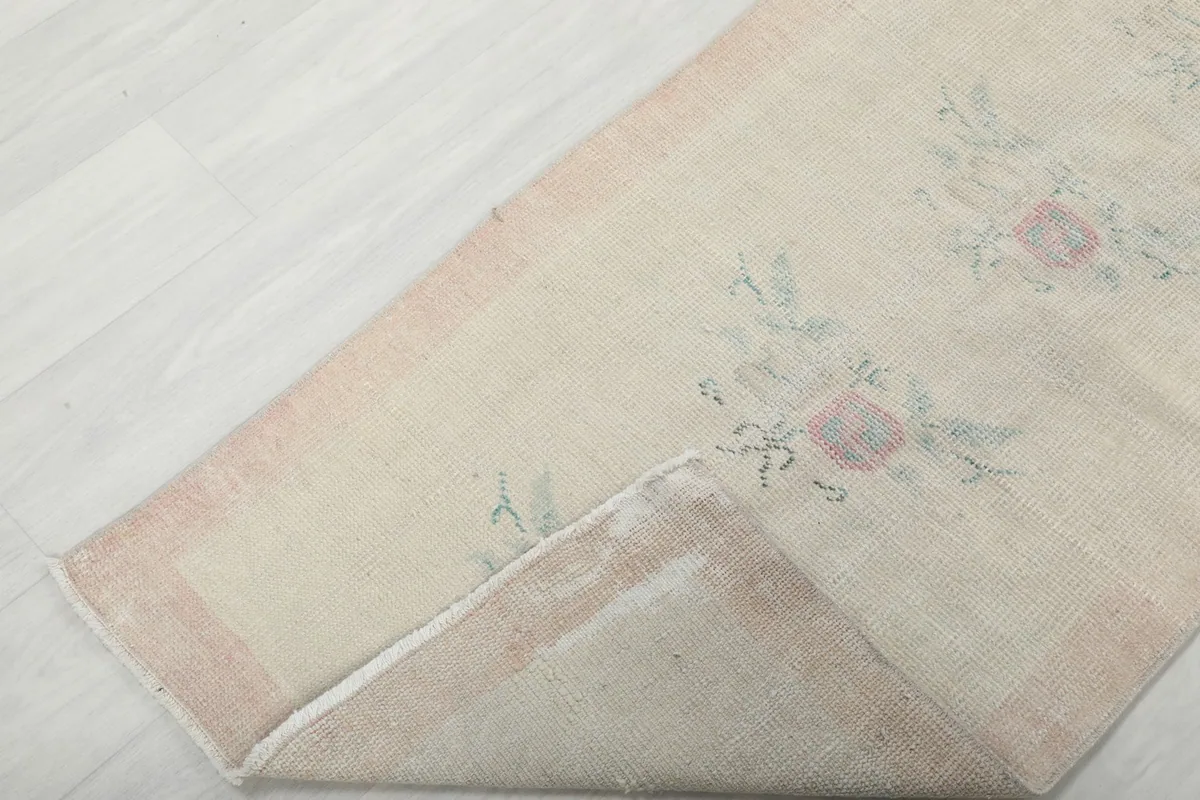 Corner of the runner rug folded back, revealing the cotton foundation and the reverse side.