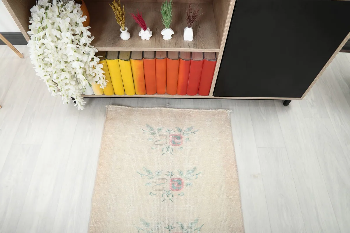 Overhead view of one end of the cream runner rug, showcasing floral motifs and faded rose border.