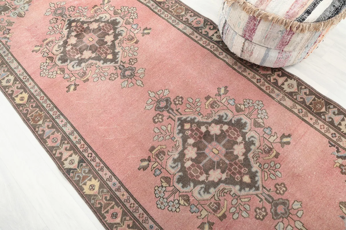 Angled view showcasing the faded rose field and intricate tribal motifs of the runner