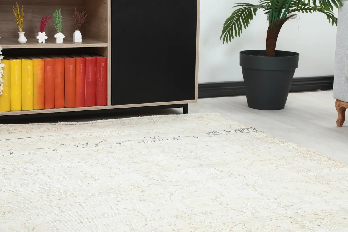 Close-up of a corner of the ivory rug, showing the subtle beige floral pattern and low pile.
