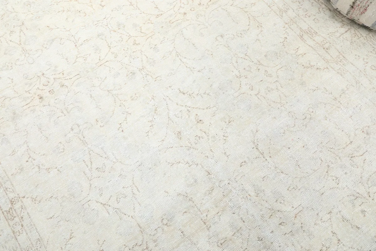 Detailed view of the rug's field, showcasing the faded floral design and texture.