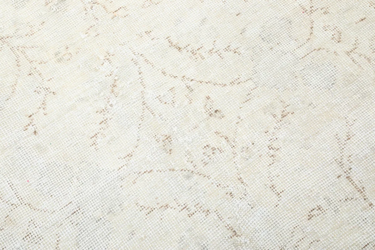 Close-up of the low wool pile and the intricate, subtle hand-knotted patterns in ivory and beige.