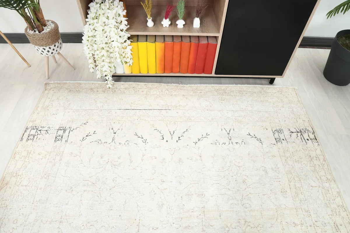 Top-down view of the rug's center, revealing the faded ivory and beige traditional motifs.