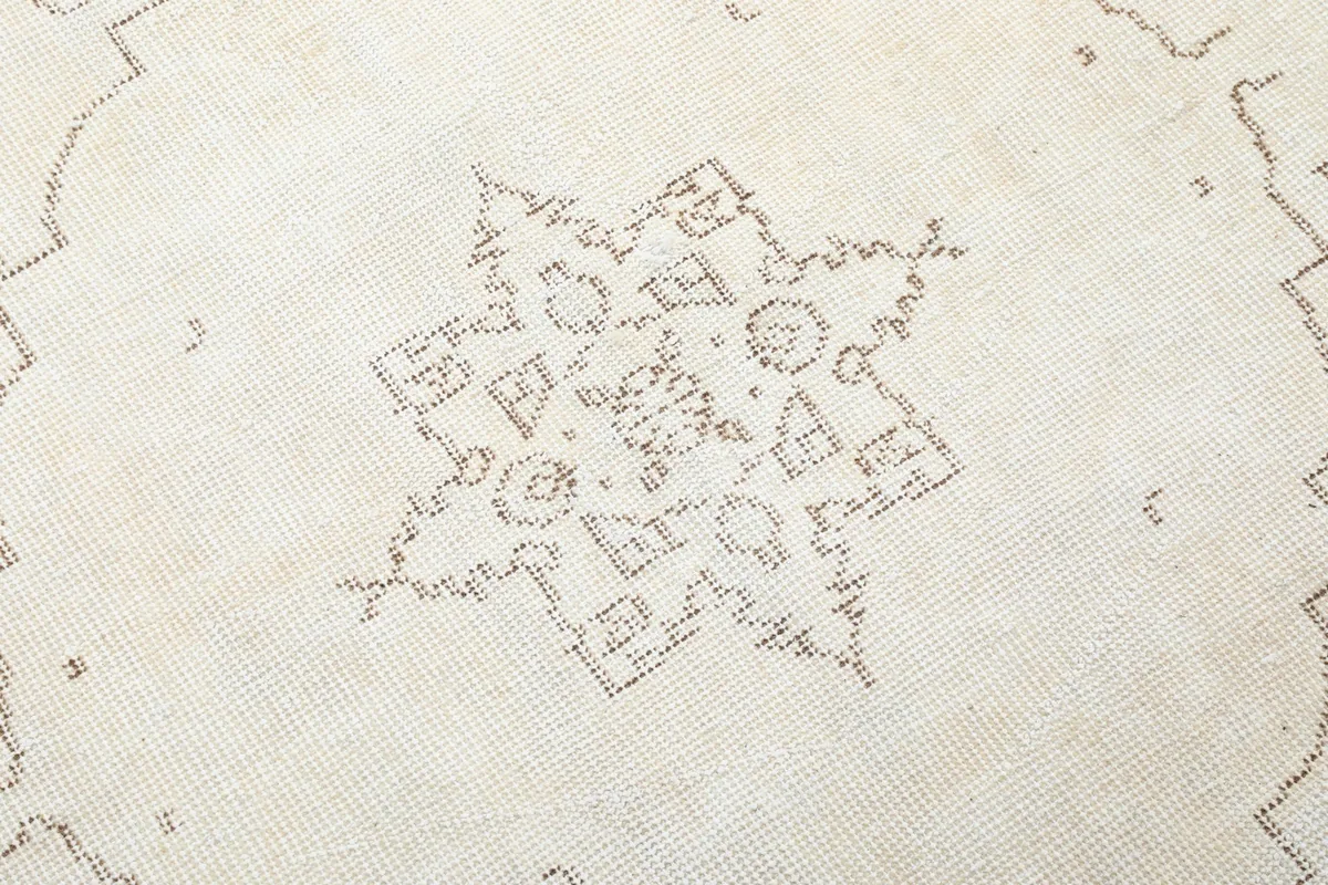 Close-up of the central star-like medallion pattern on the vintage ivory rug