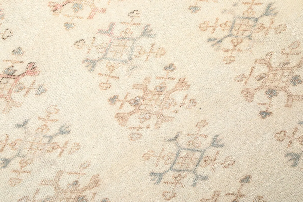 Close-up of individual hand-knotted geometric patterns on the rug's ivory field