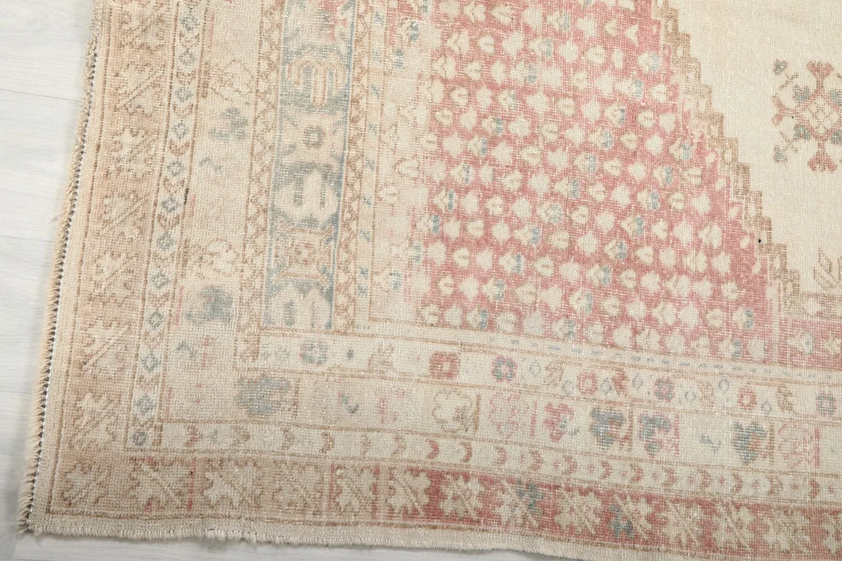 Detail of the rug's outer border, showing rose, beige, and blue patterns and fringe
