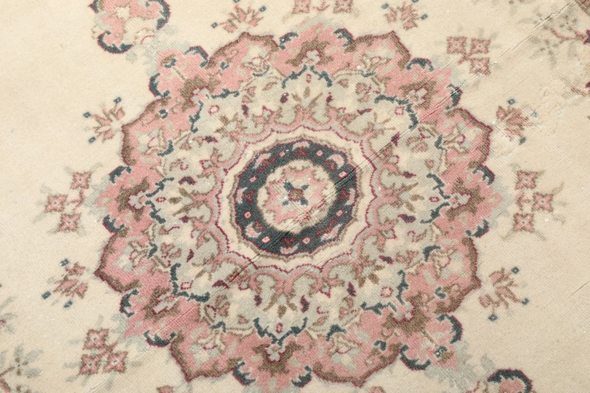 Detailed view of the central rose and blue medallion motif on the rug