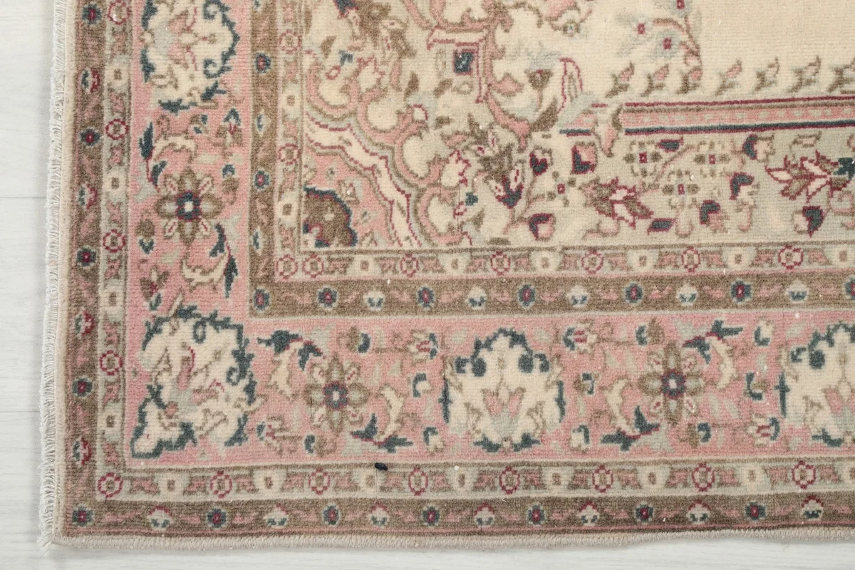 Close-up of the rug's border with floral patterns in rose, brown, and blue