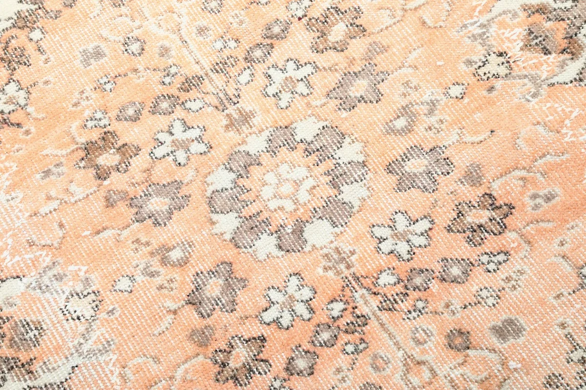 Extreme close-up showing the worn texture and muted orange and gray tones of the pile