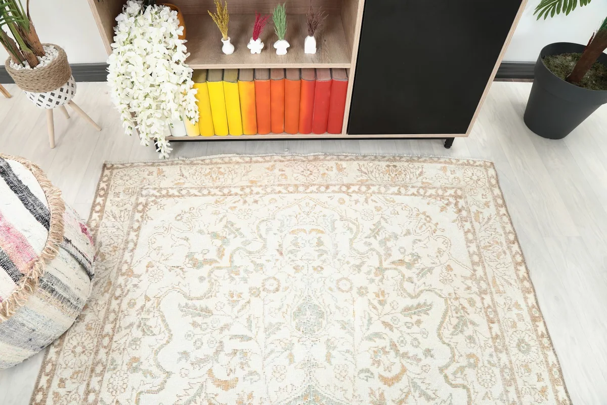 View of the rug's end, showcasing the subtle colors and motifs near a decorative pouf