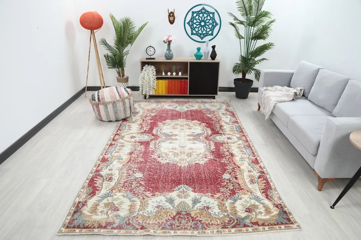 Vintage red and ivory rug in a modern living room setting with a gray sofa and plants.