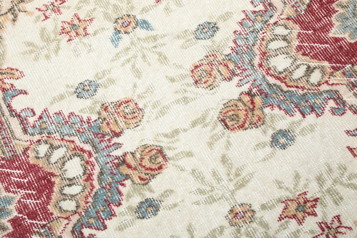 Close-up of the ivory field showing individual floral motifs in blue, red, and tan colors.