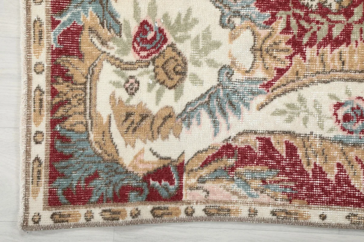 Detailed view of the rug's outer border with intricate patterns in ivory, tan, and blue.