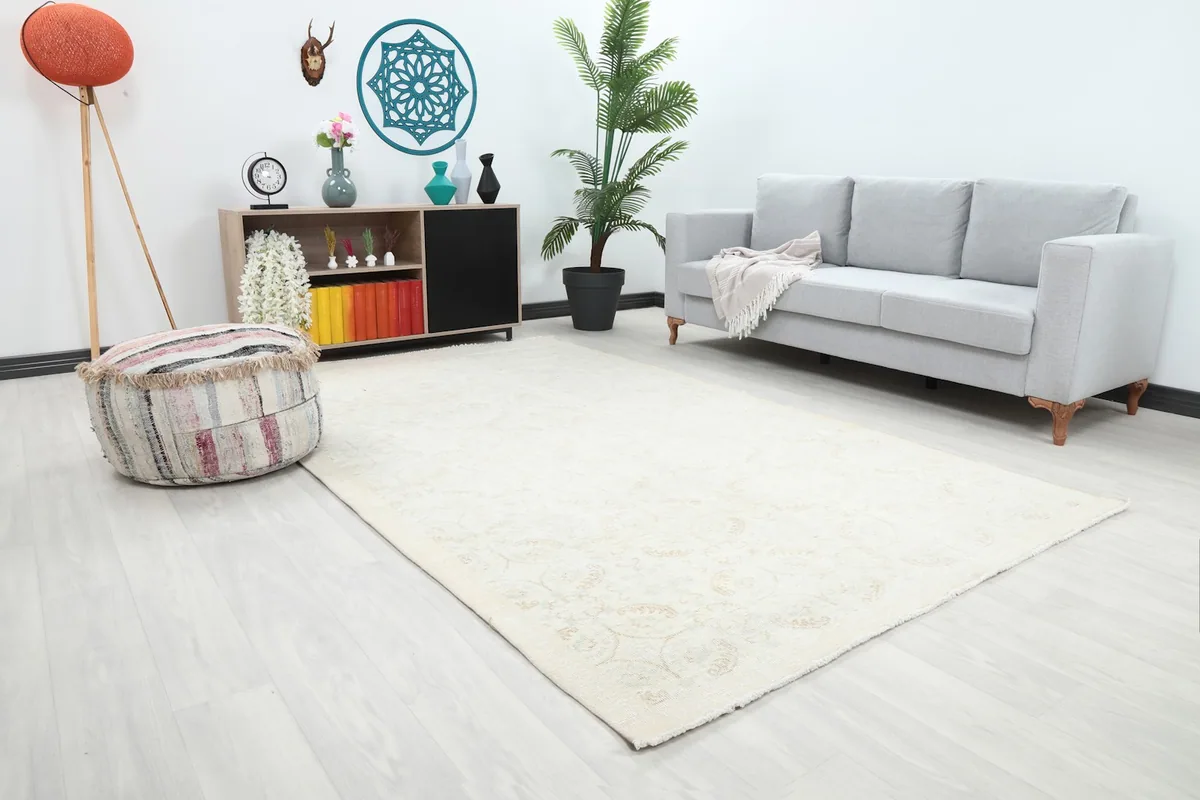 Angle view of the ivory and beige vintage rug in a living room, showing its placement relative to furniture.
