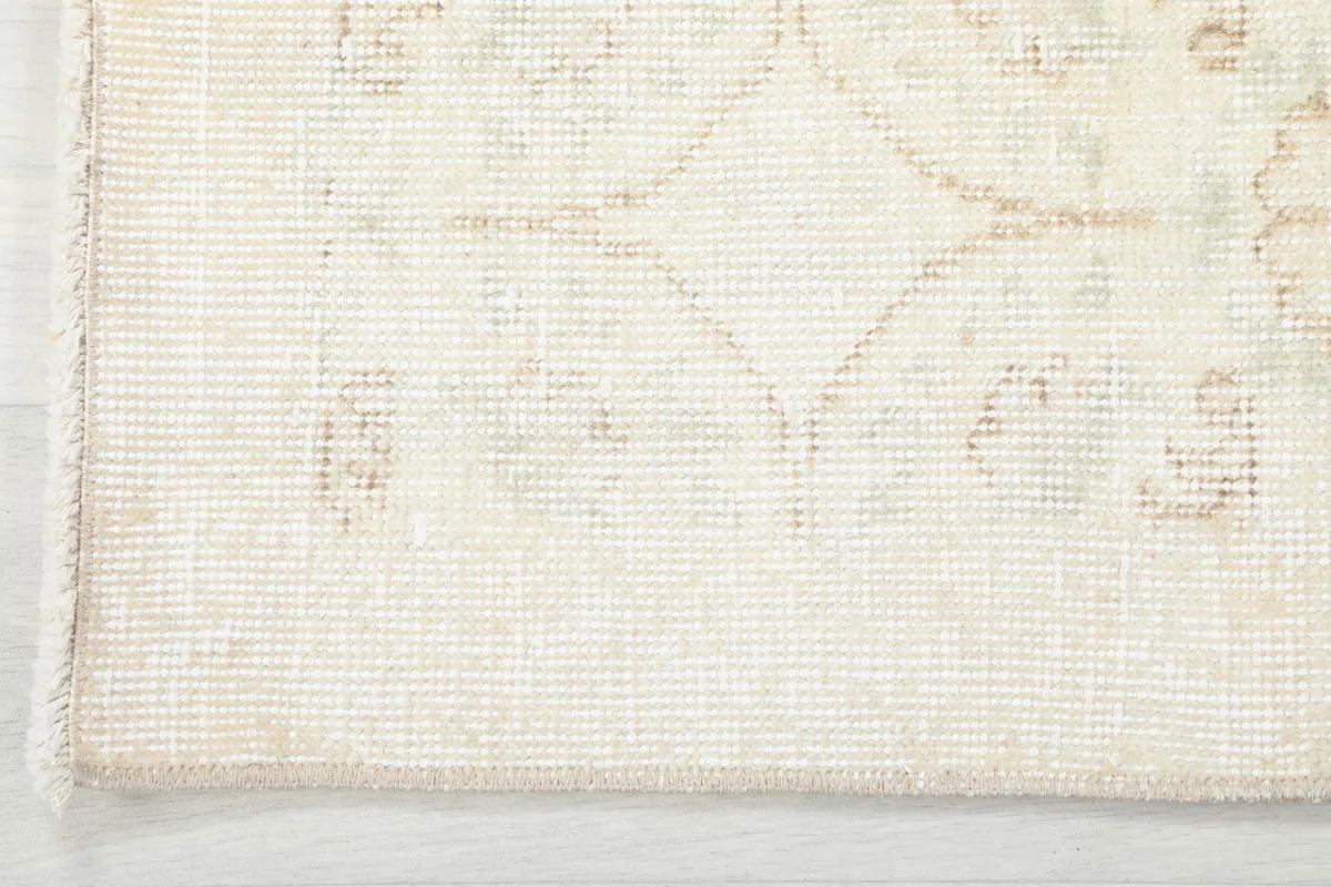 Close-up of the rug's edge, showing the subtle border design and the texture of the hand-knotted wool.