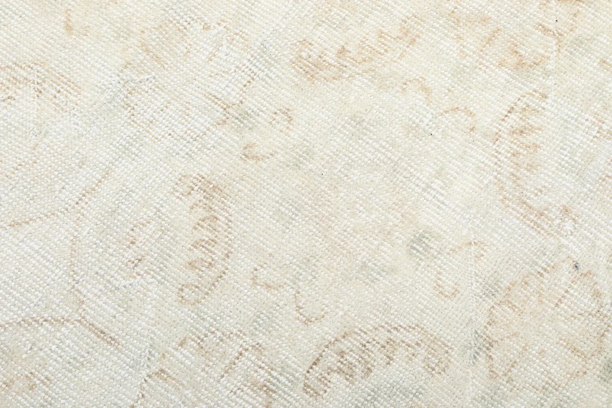 Close-up of the low wool pile and the subtle beige and green tones within the vintage rug's design.