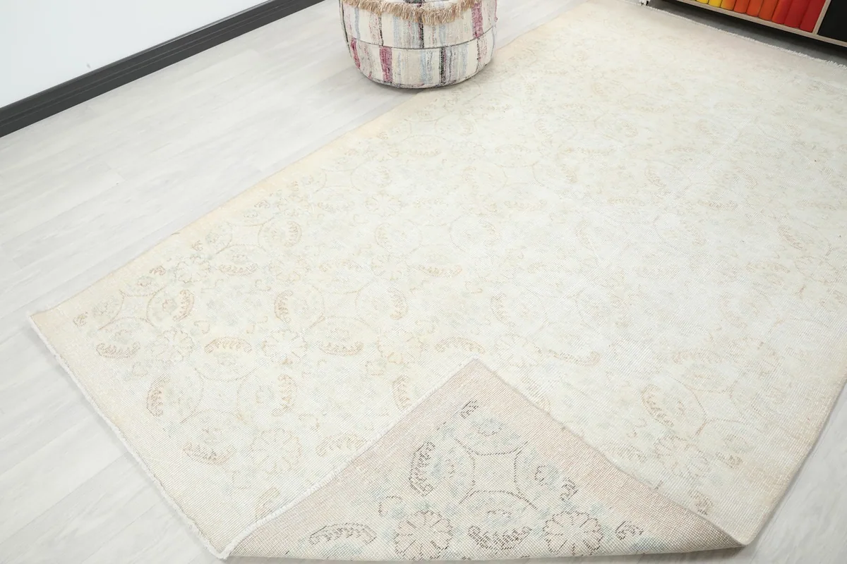 View of the rug with a corner folded back, revealing the reverse side and its hand-knotted construction.
