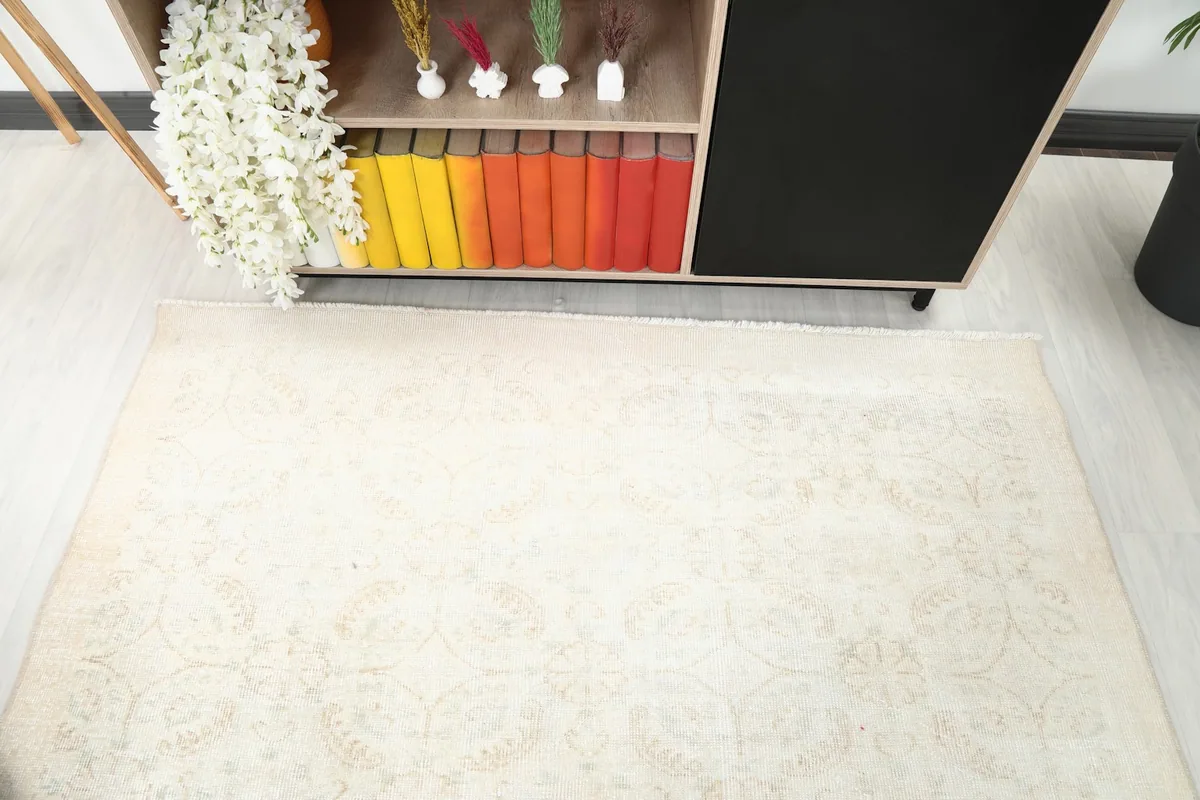 Overhead view showing the top edge of the ivory and beige rug next to a cabinet.