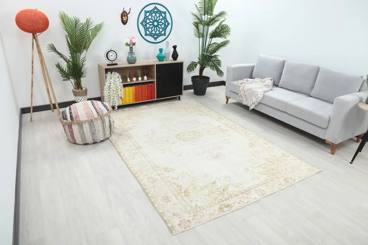 Angle view of the ivory and olive vintage rug in a living room, showing its scale relative to furniture.
