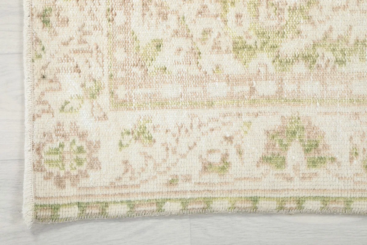 Close-up of the rug's border design with olive and tan accents, showing the edge finishing.