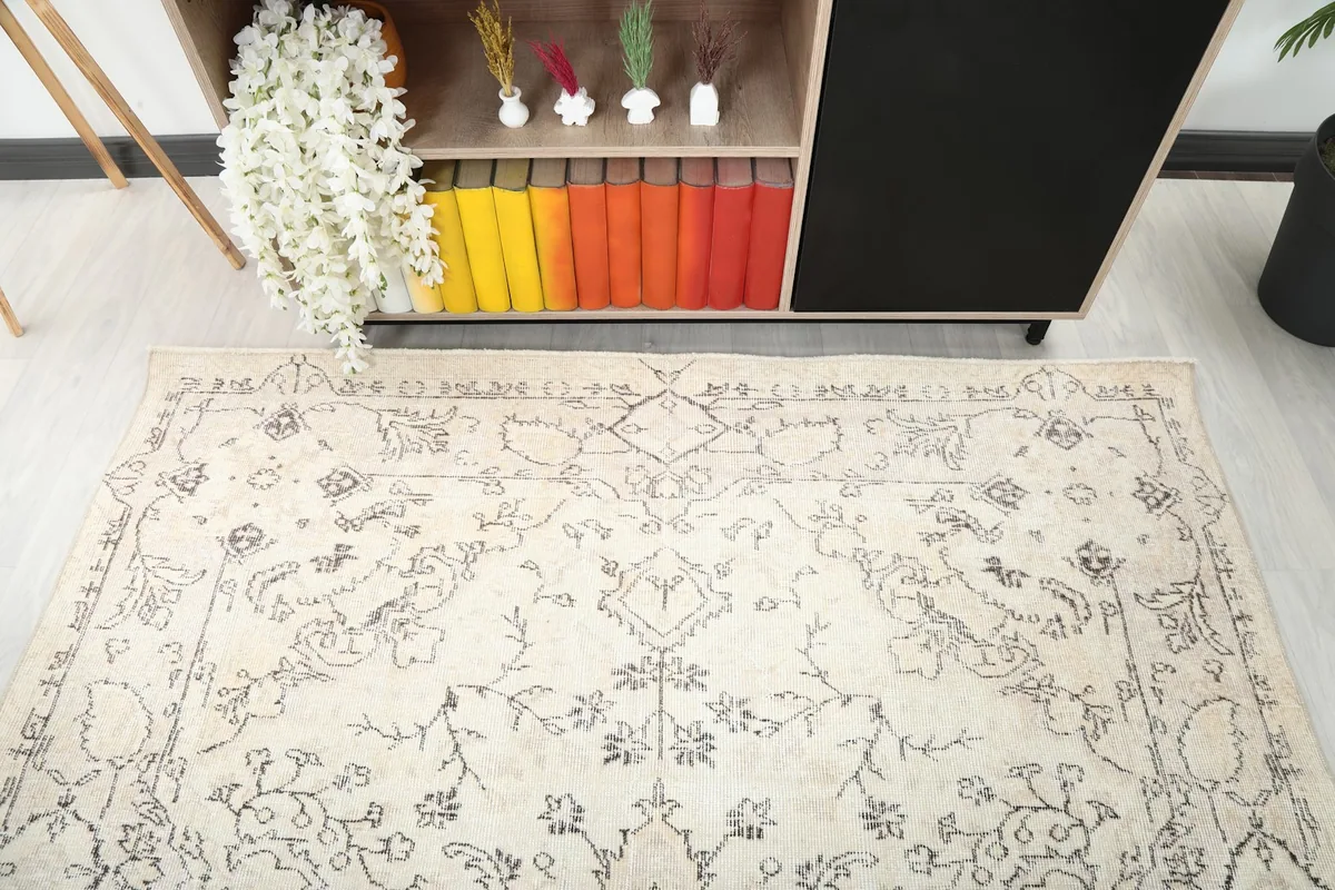 Detail view of the rug's corner and border, showing the muted gray floral motifs.
