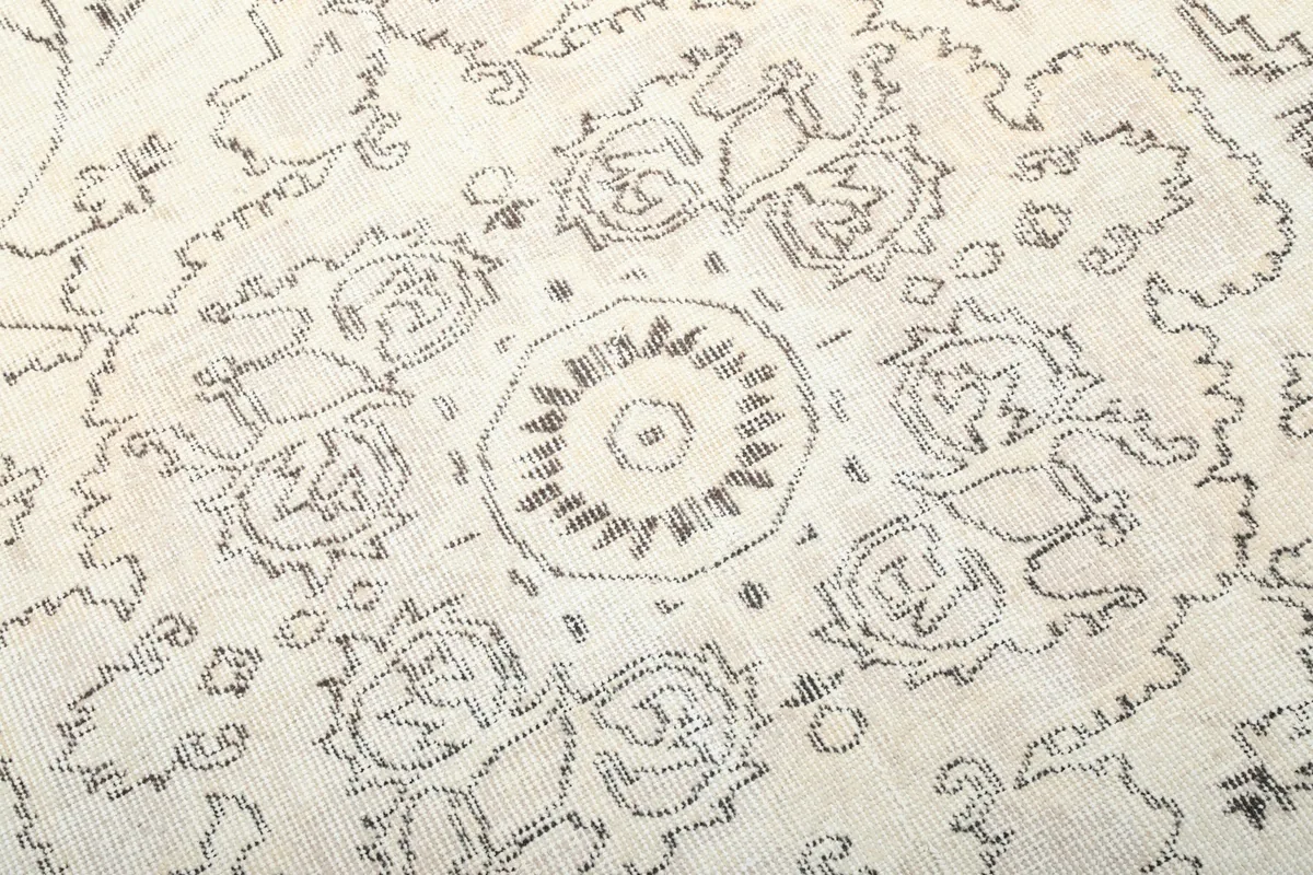 Close-up of the central medallion design, highlighting the hand-knotted wool texture and faded charcoal details.