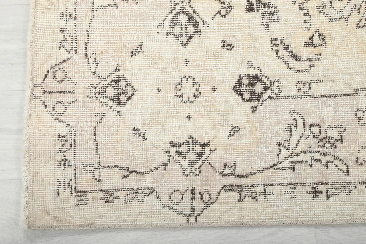 Close-up of the rug's border design, showing the intricate gray patterns and natural fringe.