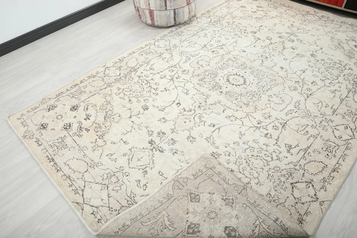 View of the rug with a corner folded back, revealing the wool pile and cotton foundation.