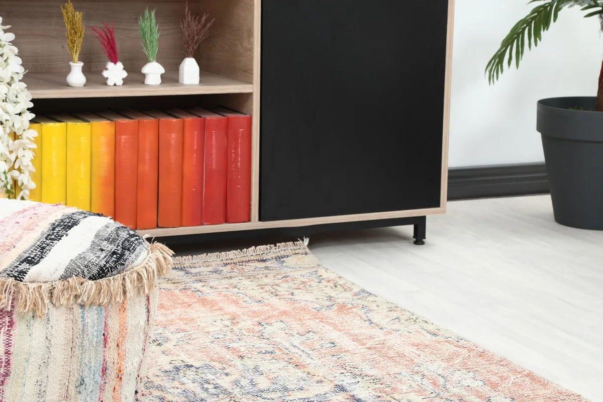 Close-up view of the runner's end in a room, showing its interaction with decor elements like an ottoman and shelf.