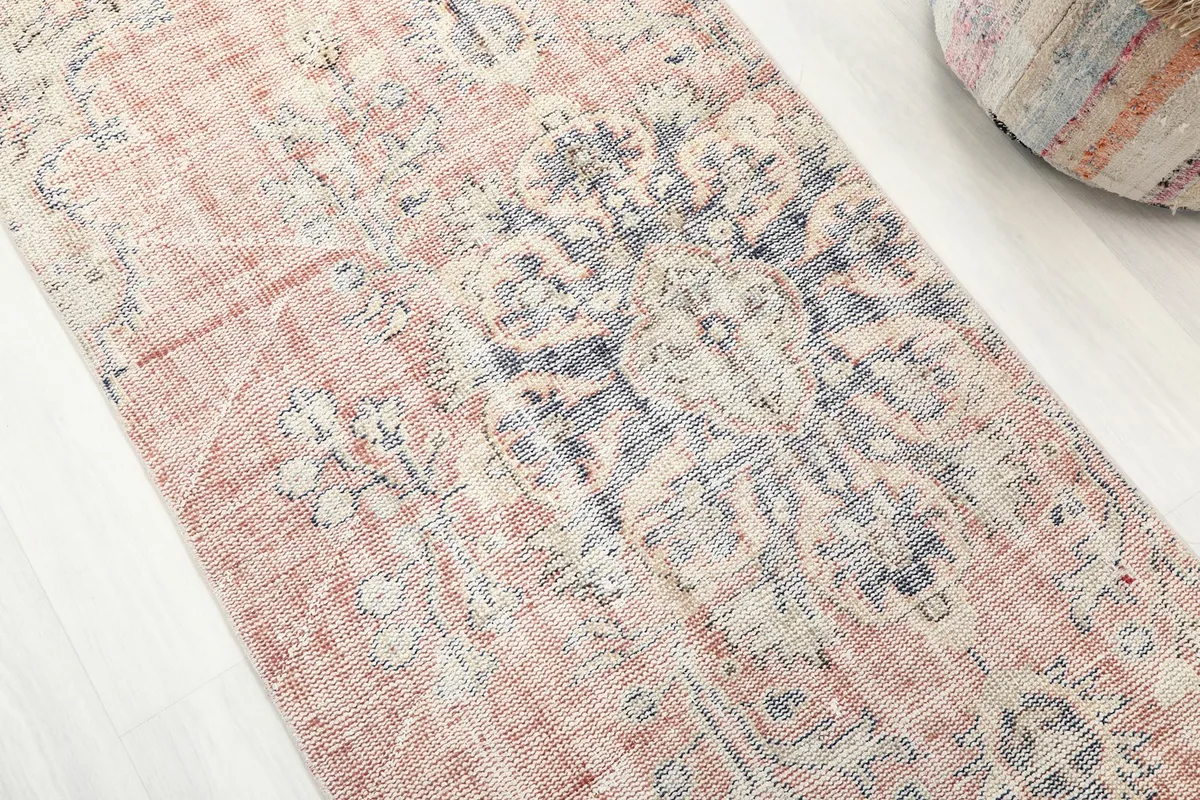 Close-up detail of the central medallion motif, showing the rose, blue, and ivory colors and vintage wear.